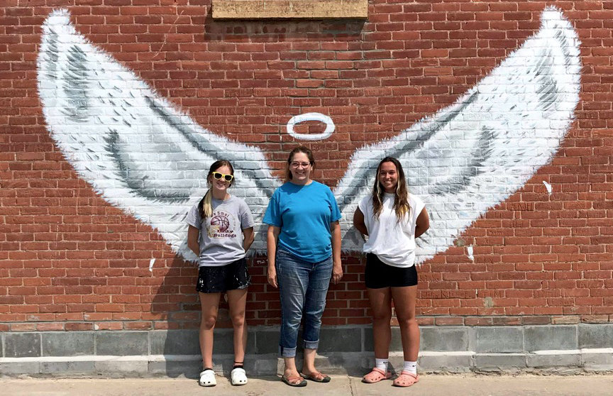 Mia Moerke, Mary Lee and Brooke Jennings pose with the new artwork outside Ward's Store & Bakery.