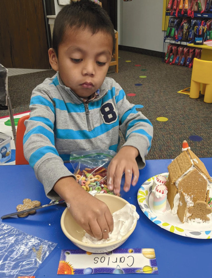 Carlos Perez Torres decorates his gingerbread house with candies and goodies.