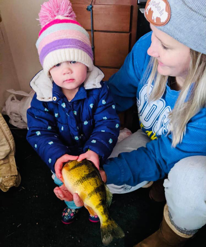 Sylvie Johnson, with her mother Taylor, isn’t sure what to think of her first fish.