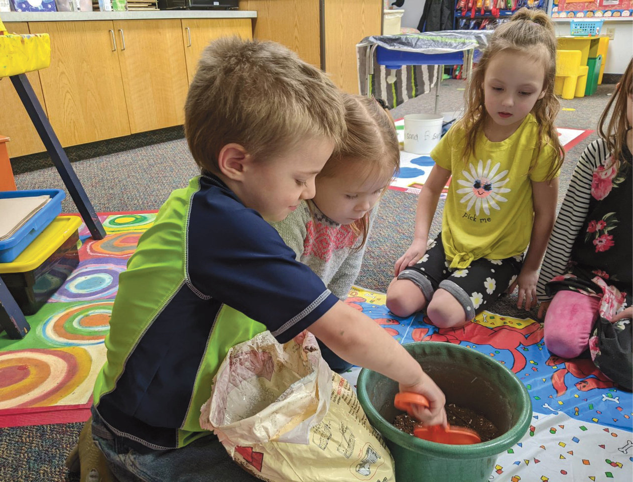 Iroquois preschoolers listened to the book "The Missing Mitten Mystery" by Steven Kellogg. Afterward, Sammy Bretz, left, Raea Guthmiller and Savannah Driggers planted a mitten, hoping it will grow into a mitten tree.