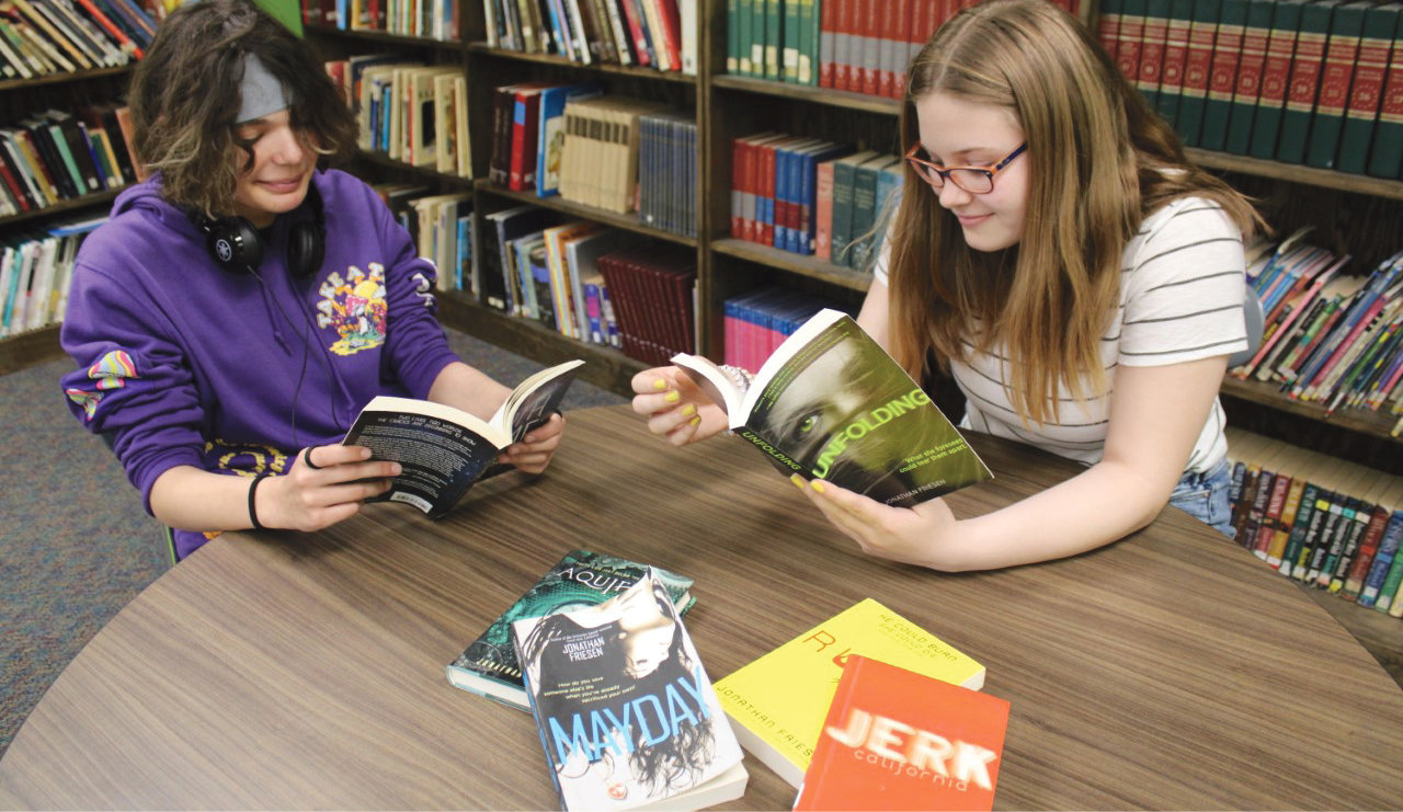 Eva Shoultz, left, and Emma Hill look at books donated by ABT.