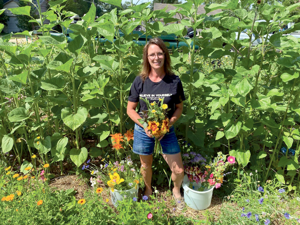 Tanya Flegel stands in her flower garden with some fresh cut flowers and one of the bouquets she made up.